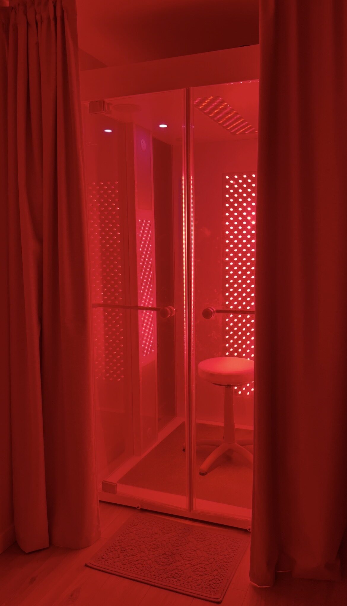 The HaloRed O2 Vitality Booth seen through glass doors, glowing with red and near-infrared light at Organically Whole