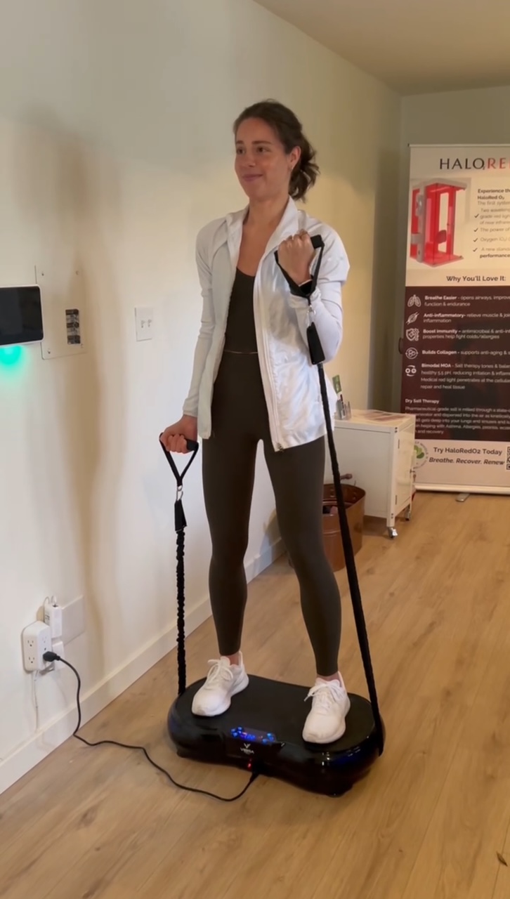 Client using the VibraTech whole body vibration platform with resistance bands